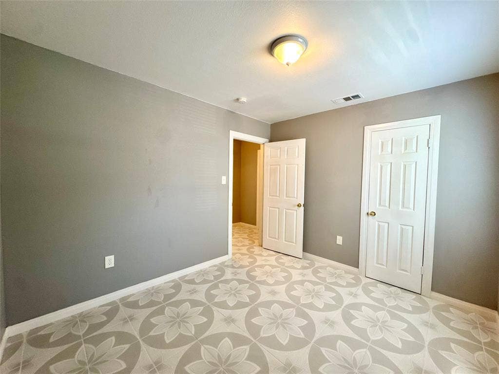 Room featuring gray walls, white baseboards, and patterned floor tile
