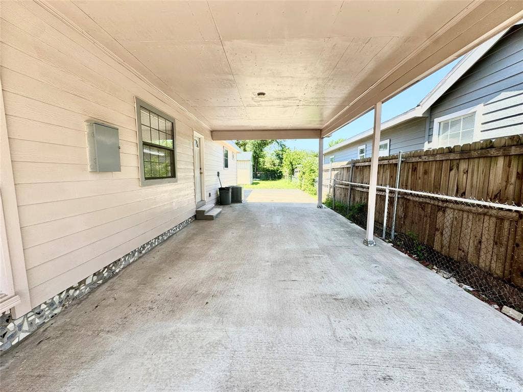 Carport with concrete flooring and a wood fence border