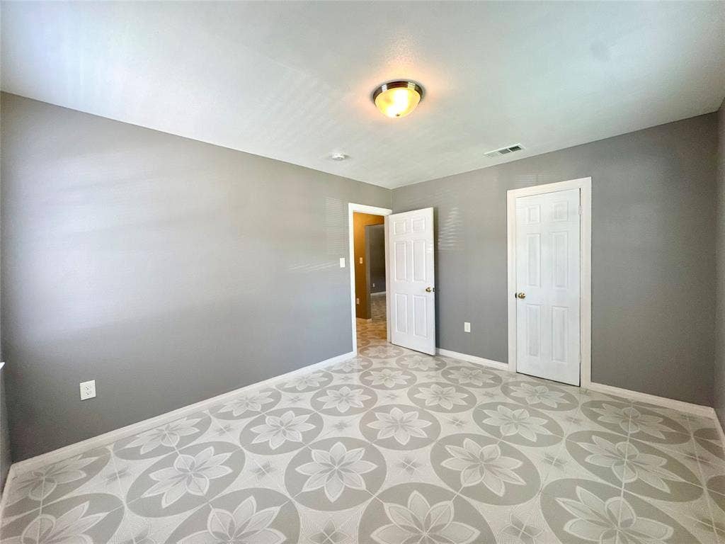 Room featuring patterned tile flooring, cool gray wall paint, and white trim