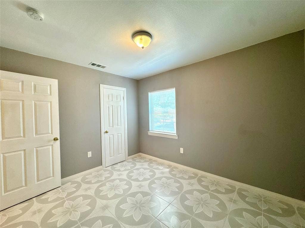 Room featuring patterned tile flooring, neutral wall tones, and a single window with white trim