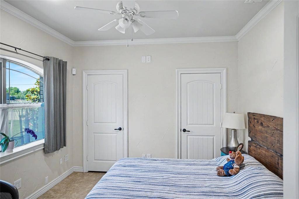 101 Friendship Circle, West Tawakoni, TX 75474 Neutral-toned room featuring crown molding, an arched window, and two paneled doors with dark hardware