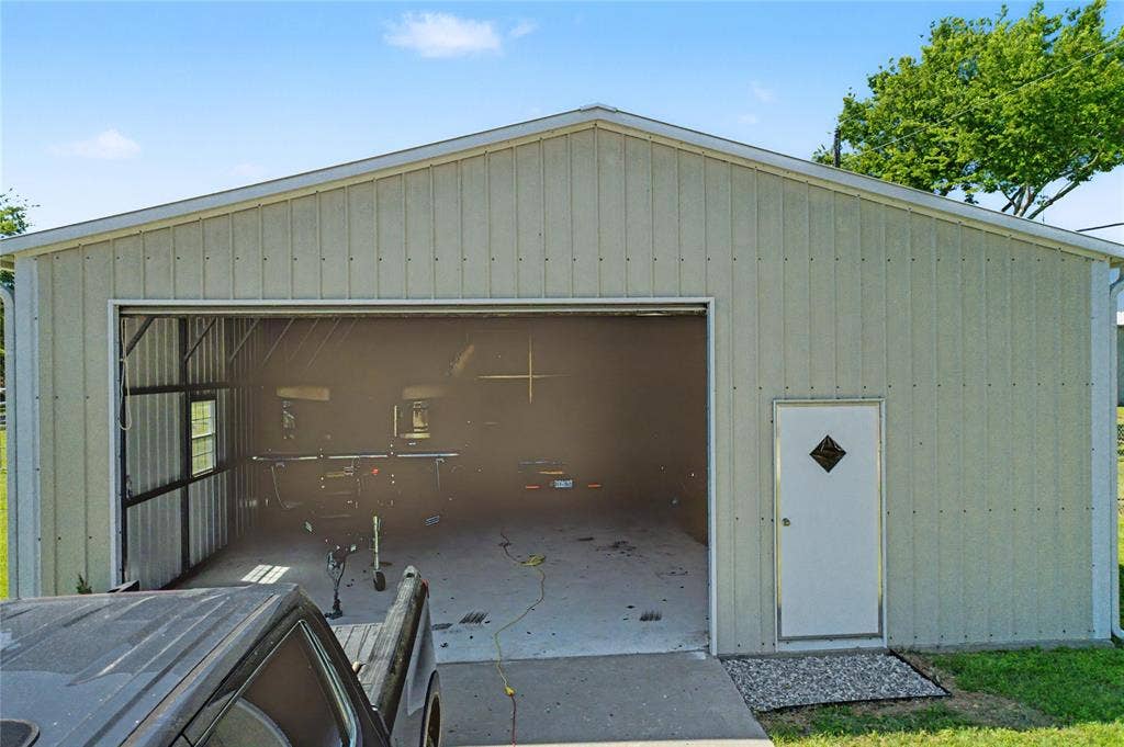 101 Friendship Circle, West Tawakoni, TX 75474 Metal-sided outbuilding with a prominent overhead door opening, an additional pedestrian entry door, and a single window