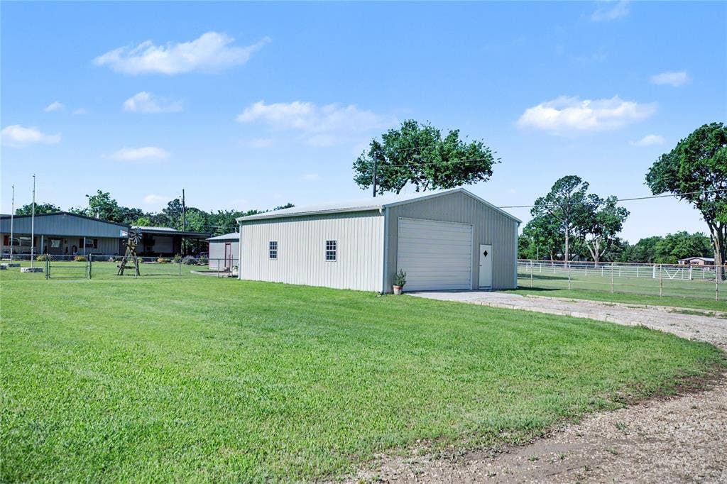 101 Friendship Circle, West Tawakoni, TX 75474 Metal-sided outbuilding featuring a roll-up garage door, pedestrian entry, and multiple windows