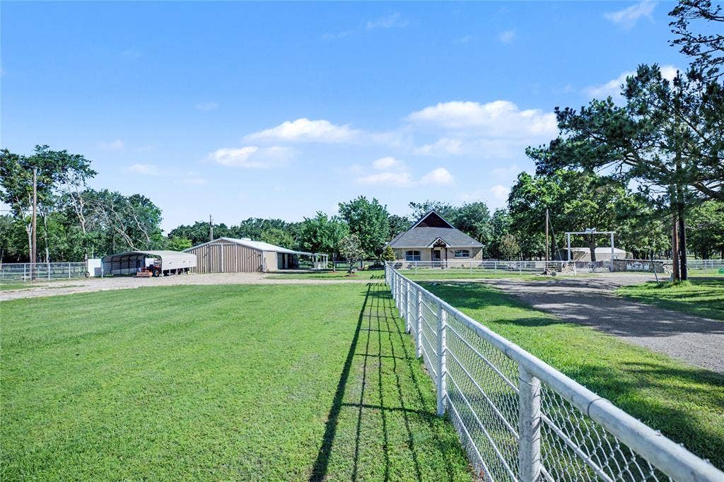 101 Friendship Circle, West Tawakoni, TX 75474 Expansive green grounds featuring a white metal fence, multiple outbuildings, and a main residence with a prominent roofline
