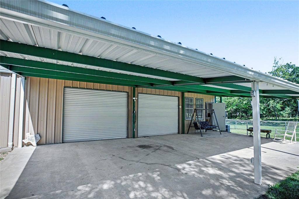 101 Friendship Circle, West Tawakoni, TX 75474 Two garage bays with roll-up doors, extended concrete pad, and a covered patio area with a metal roof