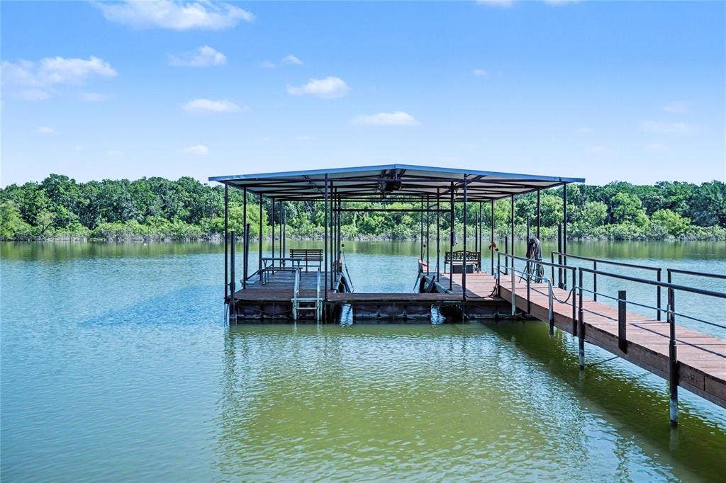 101 Friendship Circle, West Tawakoni, TX 75474 Covered boat dock featuring a metal frame, wood-finish decking, and a gangway with black metal railing