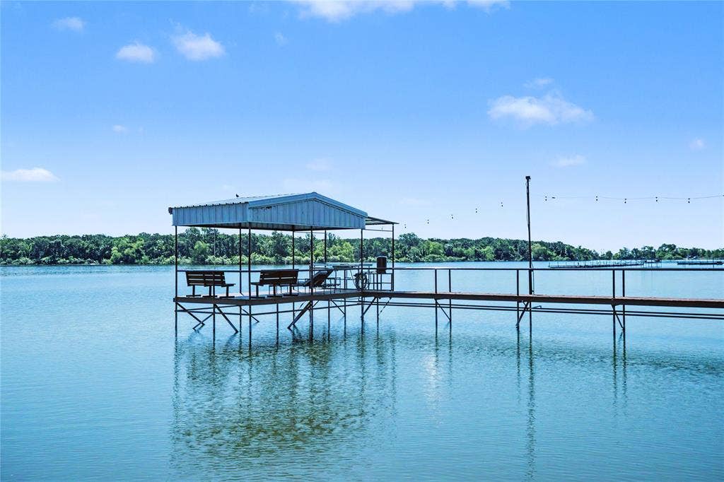 101 Friendship Circle, West Tawakoni, TX 75474 Private dock featuring a covered seating area with a metal roof, open-air walkway, and string lighting