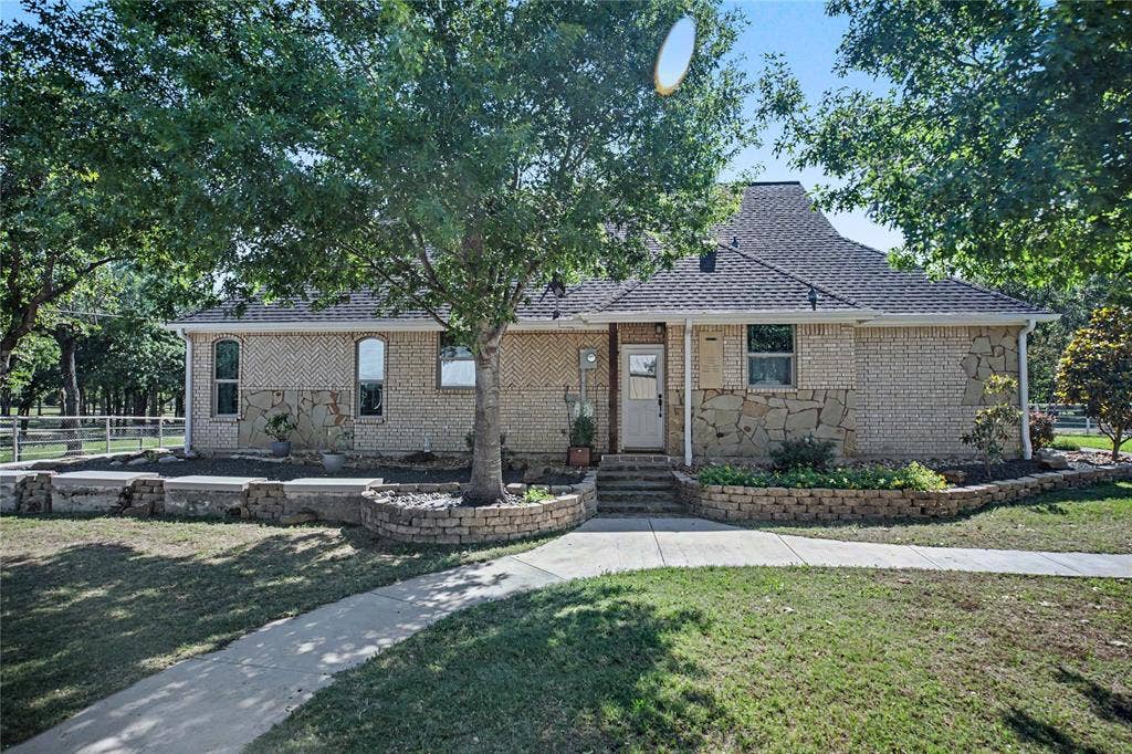 101 Friendship Circle, West Tawakoni, TX 75474 Brick and stone exterior featuring multiple mature trees