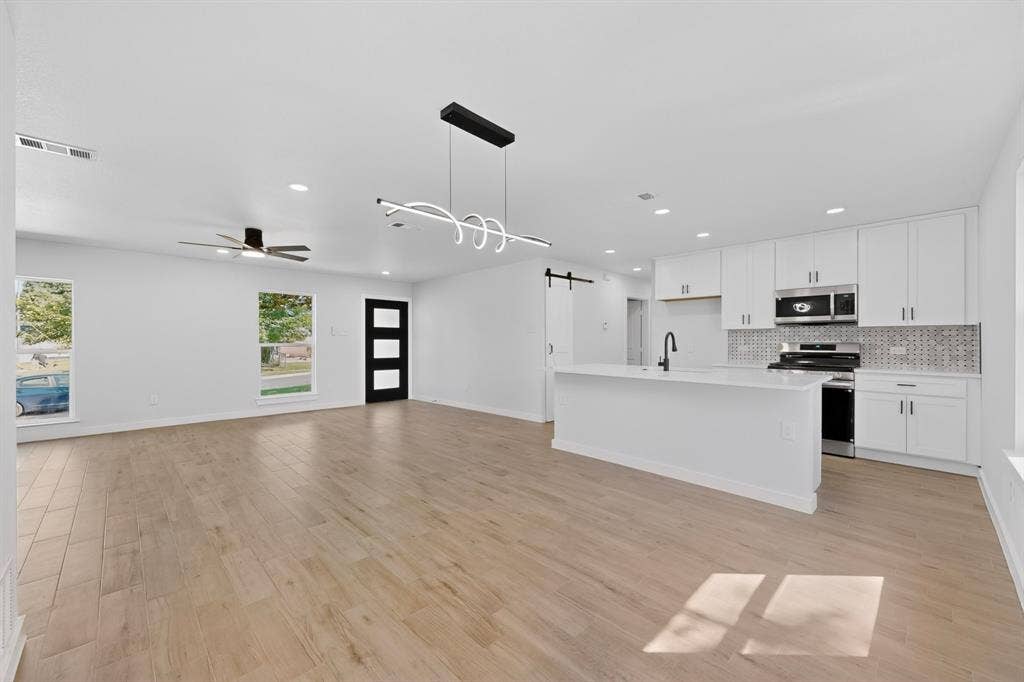 3853 Happy Canyon Drive, Dallas, TX 75241 Spacious open-concept living area featuring wood-finish flooring and a contemporary linear light fixture