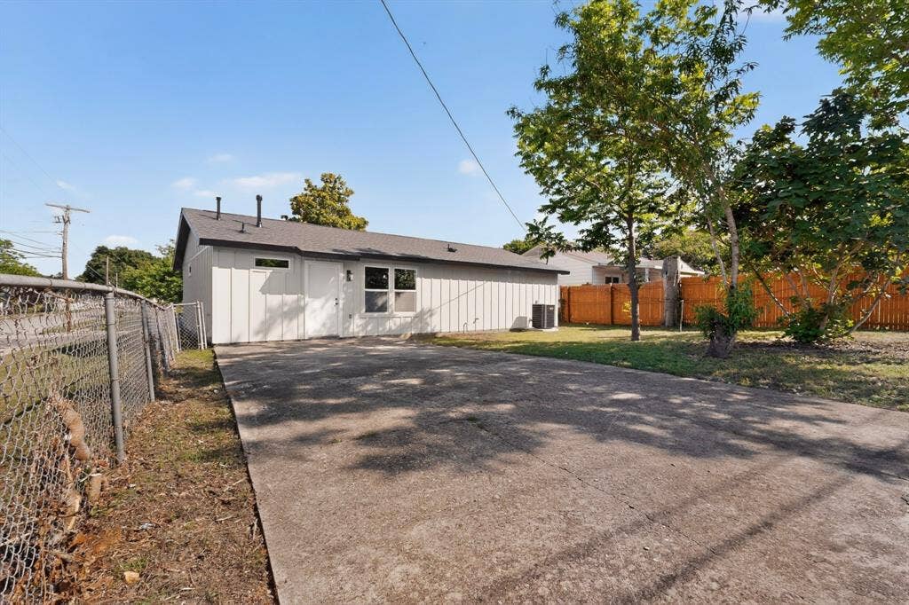 3853 Happy Canyon Drive, Dallas, TX 75241 Single-story residence featuring a gray exterior with vertical paneling, a dark shingle roof, and multiple windows