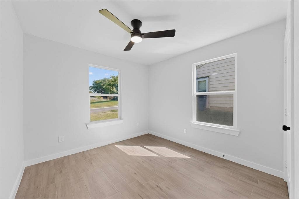 3853 Happy Canyon Drive, Dallas, TX 75241 Bright room featuring two windows, light wood-finish flooring, white baseboards, and a contemporary ceiling fan with lighting