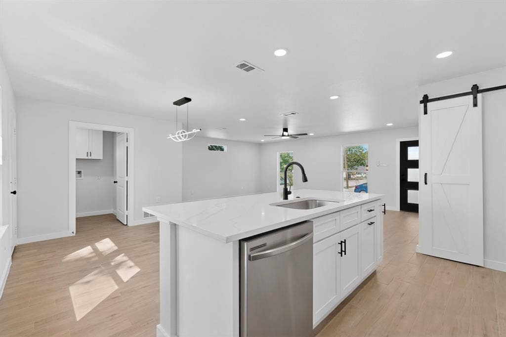 3853 Happy Canyon Drive, Dallas, TX 75241 Open-concept kitchen featuring a large island with white cabinetry, stainless steel dishwasher, and a matte black gooseneck faucet