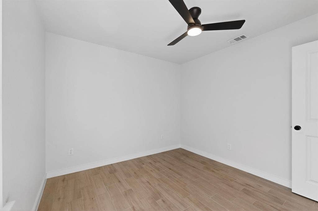 3853 Happy Canyon Drive, Dallas, TX 75241 Neutral white walls, wood-finish flooring, and a contemporary ceiling fan with integrated lighting