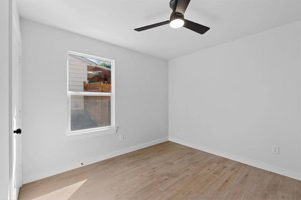 3853 Happy Canyon Drive, Dallas, TX 75241 Room featuring light-toned wood-finish flooring, a contemporary ceiling fan with integrated lighting, a single window, and a white interior door with matte black hardware