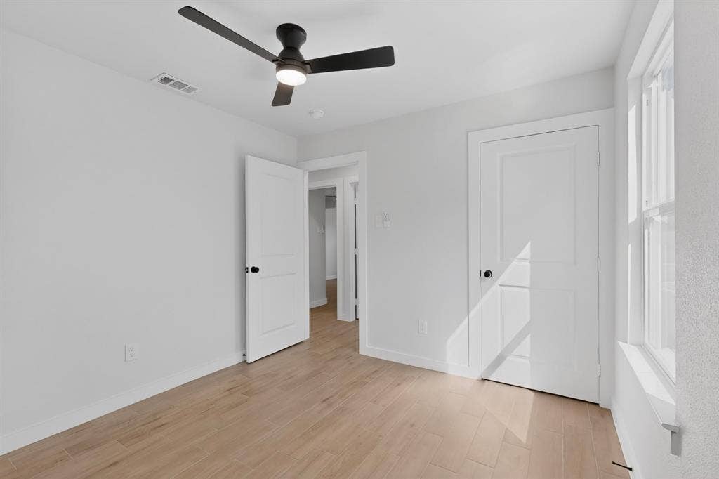 3853 Happy Canyon Drive, Dallas, TX 75241 Interior room featuring wood-finish flooring, white walls, and a contemporary black ceiling fan with integrated lighting