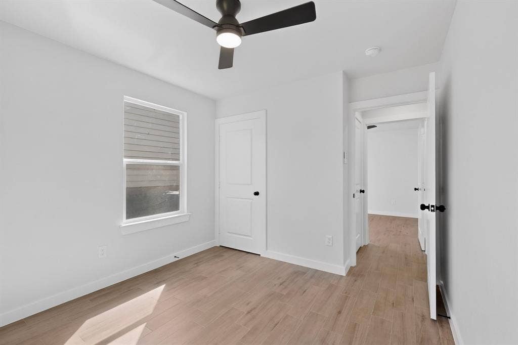 3853 Happy Canyon Drive, Dallas, TX 75241 Room featuring light wood-finish flooring, white walls, and a modern black ceiling fan with integrated lighting
