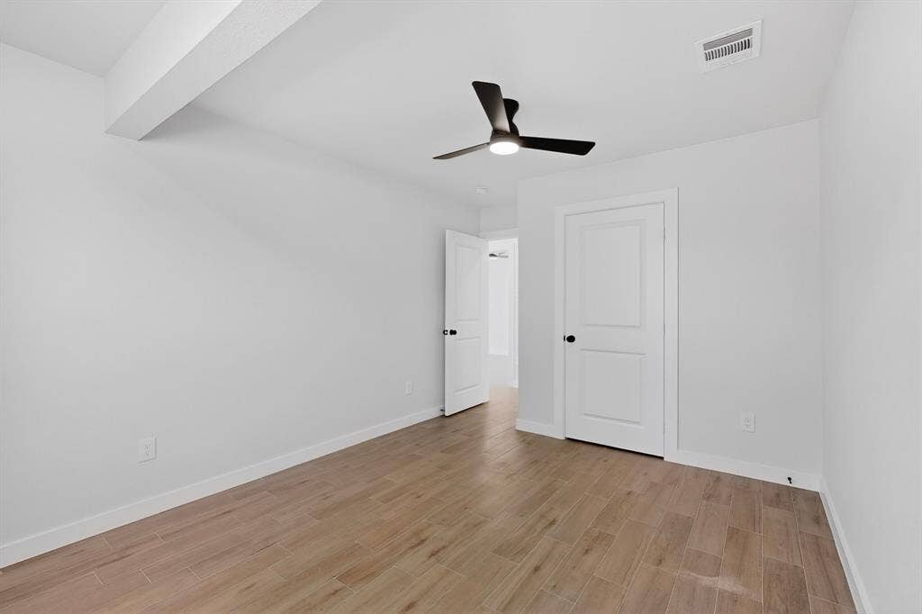3853 Happy Canyon Drive, Dallas, TX 75241 Bright room with wood-finish tile flooring, a modern black ceiling fan, white walls, and white paneled doors