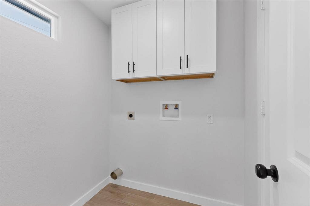 3853 Happy Canyon Drive, Dallas, TX 75241 Utility space featuring white shaker-style cabinetry with black hardware, wood-finish flooring, and a high transom window