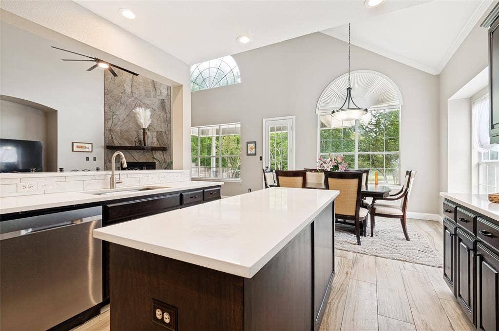 108 Appalachian Way, McKinney, TX 75071 Open-concept kitchen featuring a large central island with light-toned countertops, dark wood cabinetry, and wood-finish flooring