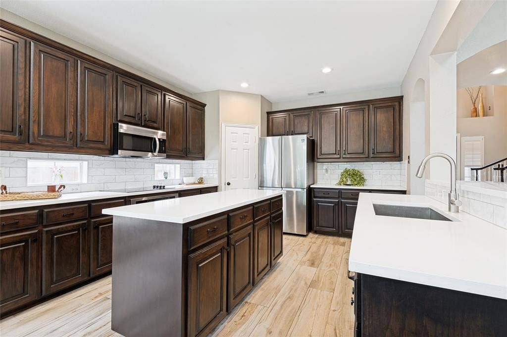 108 Appalachian Way, McKinney, TX 75071 Kitchen featuring dark wood cabinetry, stainless steel appliances, a white subway tile backsplash, light countertops, and wood-finish flooring