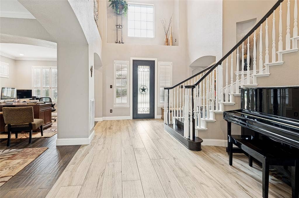 108 Appalachian Way, McKinney, TX 75071 Two-story foyer featuring wood-finish flooring, a dark entry door with decorative glass, and a grand staircase with white spindles and a dark handrail