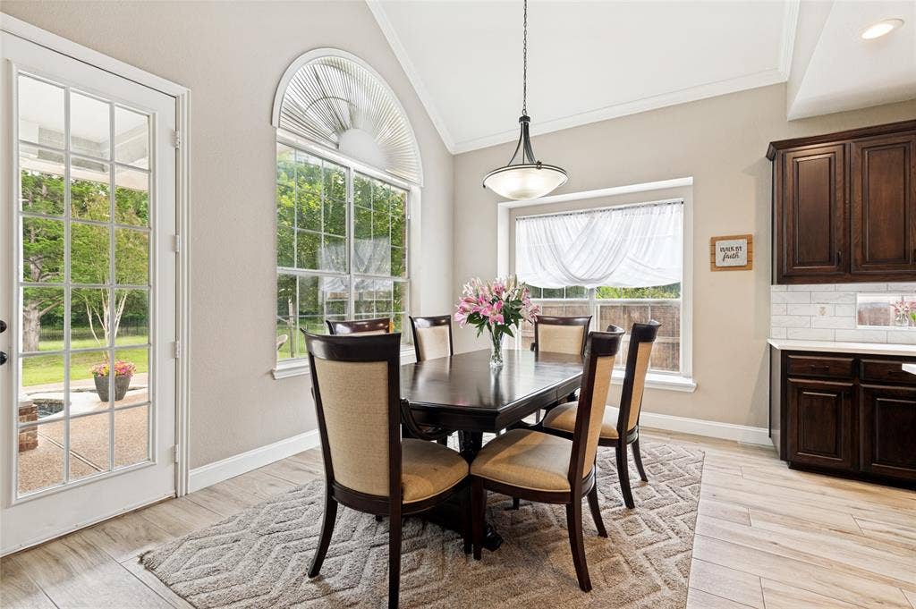 108 Appalachian Way, McKinney, TX 75071 Vaulted ceiling dining area featuring a large arched window, a glass-paned exterior door, wood-finish flooring, and crown molding
