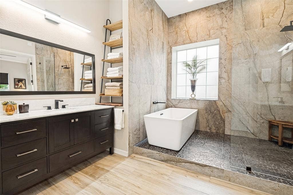 108 Appalachian Way, McKinney, TX 75071 Bathroom featuring a freestanding soaking tub and a walk-in shower with stone tile walls