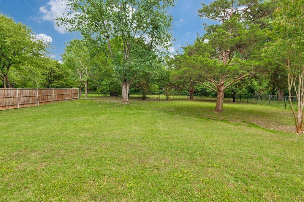 108 Appalachian Way, McKinney, TX 75071 Expansive backyard featuring a manicured lawn, mature trees, a wooden privacy fence, and a chain-link fence
