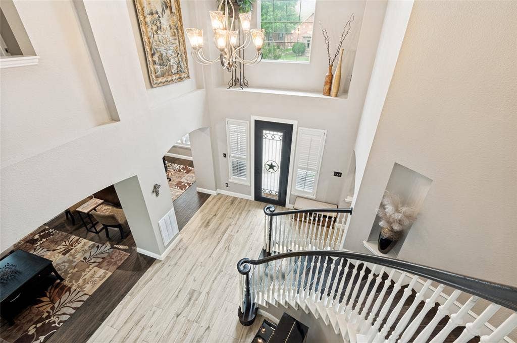 108 Appalachian Way, McKinney, TX 75071 Two-story foyer featuring a curved staircase with dark wood handrails and white balusters, light wood-finish flooring, and a decorative chandelier
