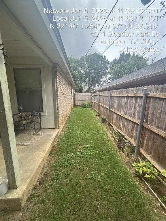 4211 Meadow Park Drive, Arlington, TX 76017 Side yard featuring a manicured lawn, full-height wooden privacy fence, and brick exterior