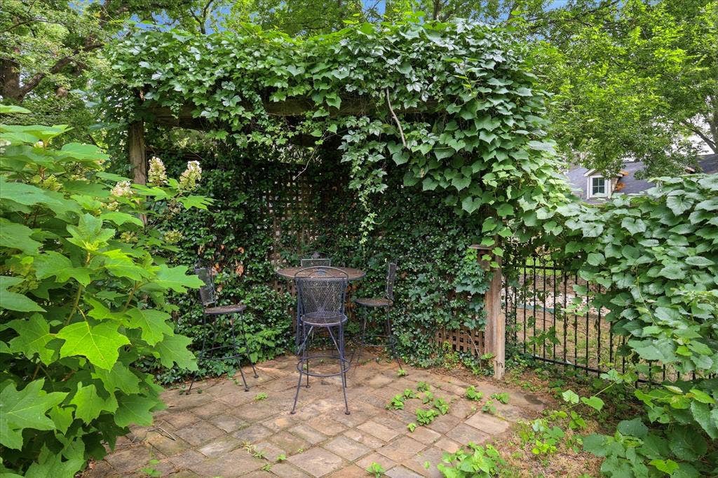 413 Collins Street, Argyle, TX 76226 Outdoor patio area featuring a wooden pergola covered in lush foliage, a lattice privacy screen, and a paved brick surface