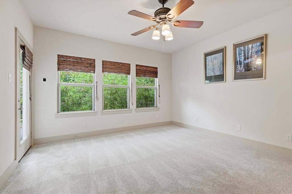 413 Collins Street, Argyle, TX 76226 Bright room featuring three sash windows with woven wood blinds, a glass-paneled door, and a ceiling fan with light kit