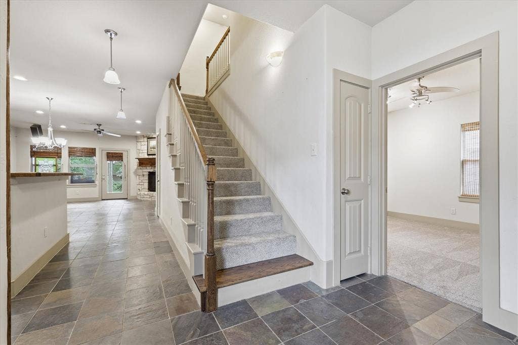 413 Collins Street, Argyle, TX 76226 Open concept interior featuring slate tile flooring, a carpeted staircase with wood handrails, and a dedicated room with carpeted flooring