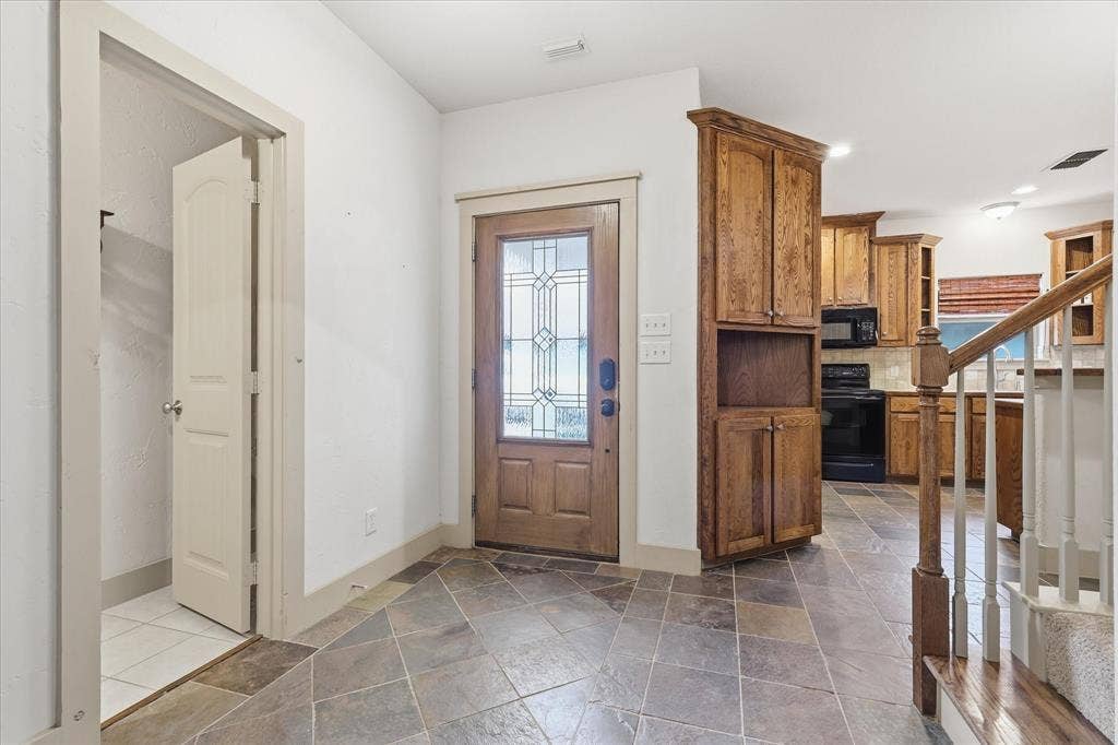 413 Collins Street, Argyle, TX 76226 Entryway featuring slate tile flooring, a wood-finish front door with decorative glass, and a built-in wood-finish cabinet