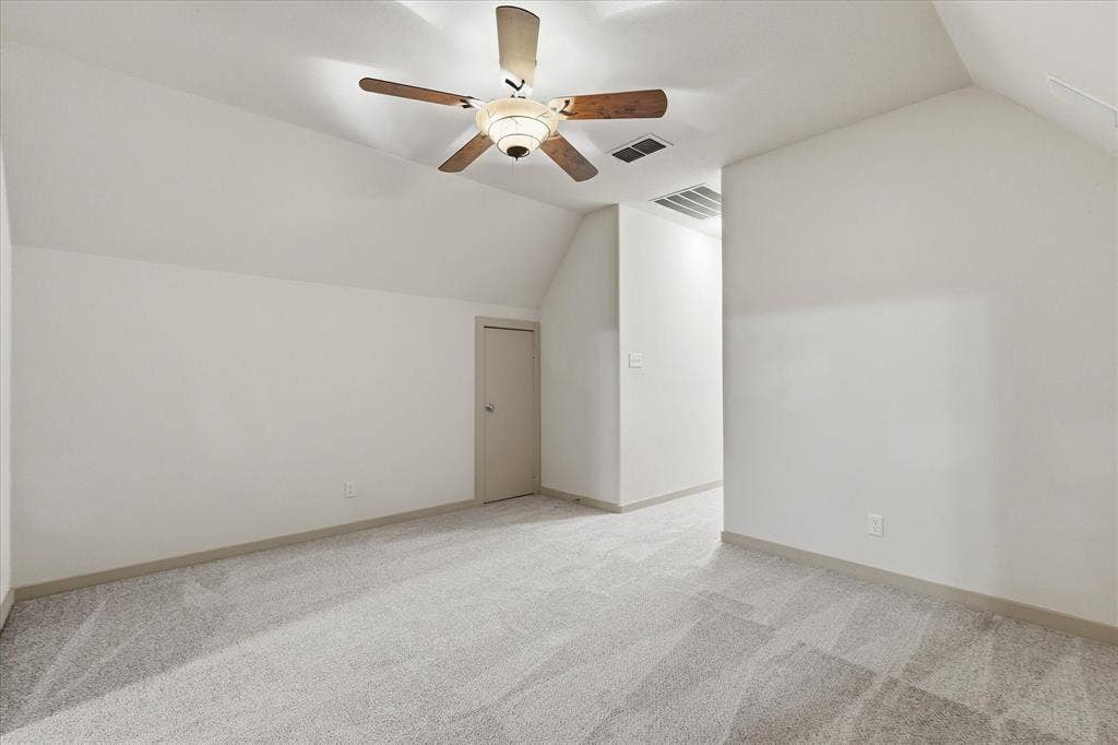 413 Collins Street, Argyle, TX 76226 Attic space featuring sloped ceilings, light gray carpeting, and a ceiling fan with wood-finish blades