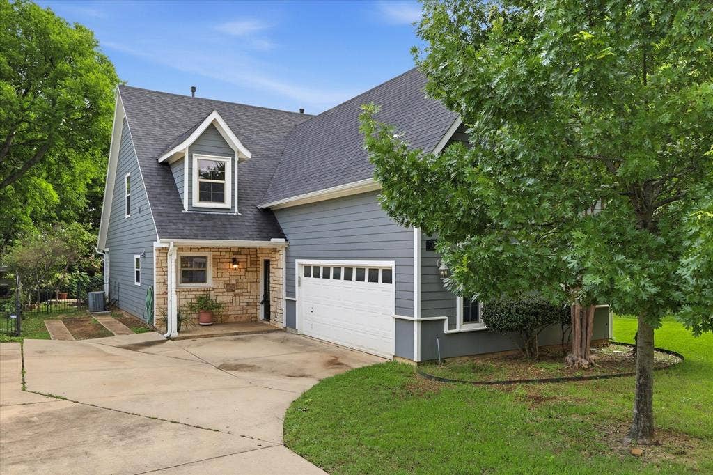 413 Collins Street, Argyle, TX 76226 Contemporary two-story exterior featuring a dormer window, stone accents, and a two-car garage with a white sectional door