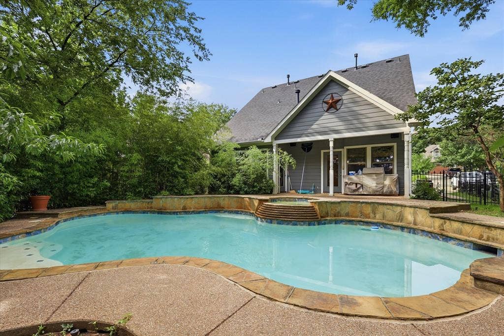 413 Collins Street, Argyle, TX 76226 Custom-shaped swimming pool featuring a stone surround and integrated spa with tiered steps
