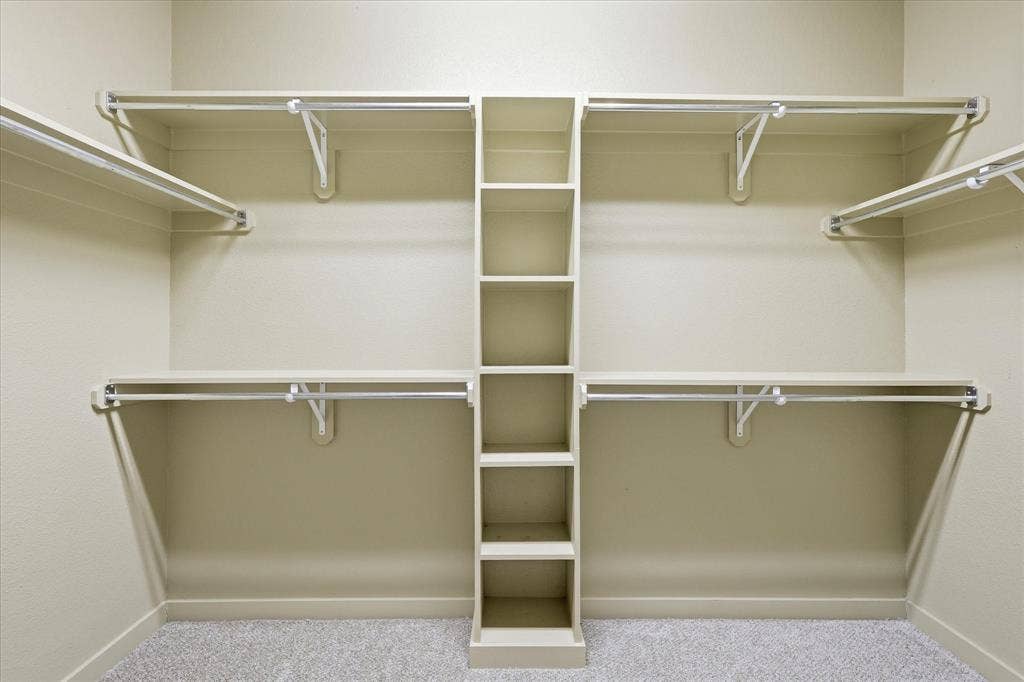413 Collins Street, Argyle, TX 76226 Walk-in closet featuring built-in shelving, multiple hanging rods, corner shelving, wall-to-wall carpeting, and neutral wall paint