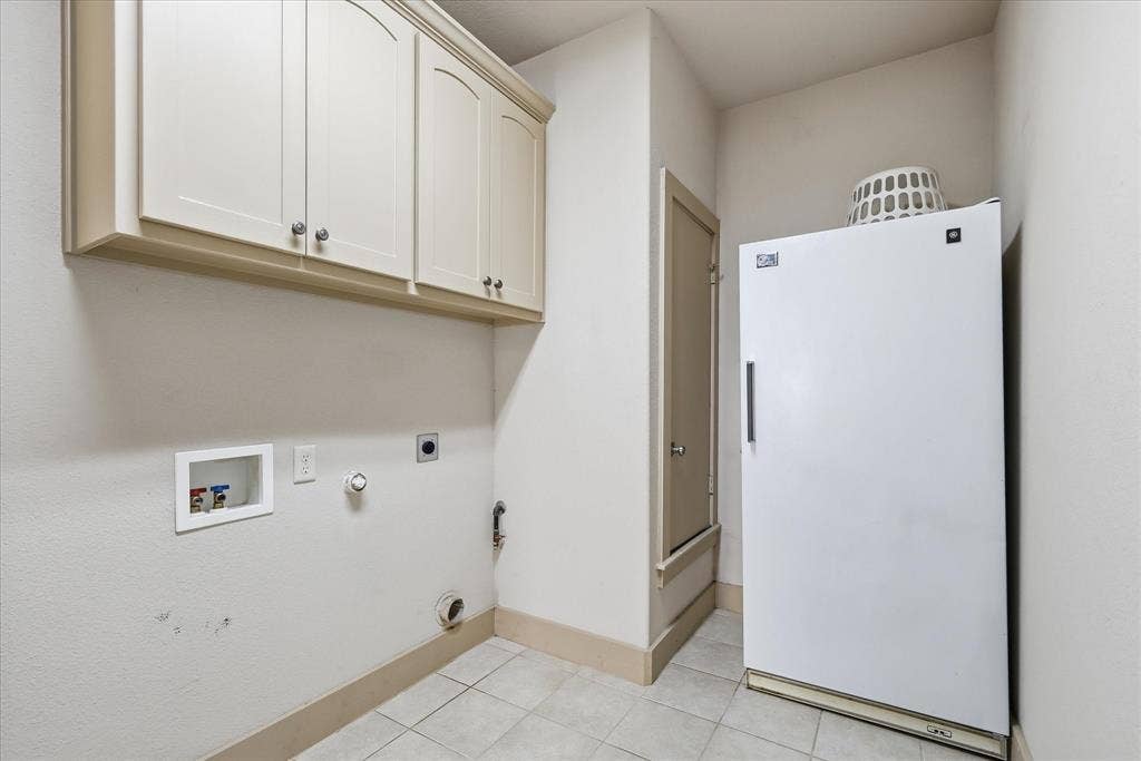 413 Collins Street, Argyle, TX 76226 Functional utility area featuring upper cabinetry with arched panel doors, tile flooring, and wall-mounted plumbing connections