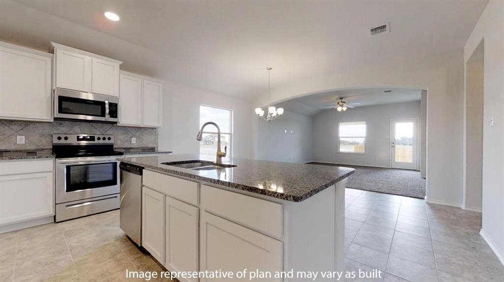 Kitchen featuring white cabinetry, stainless steel appliances, speckled countertops, and a tiled backsplash