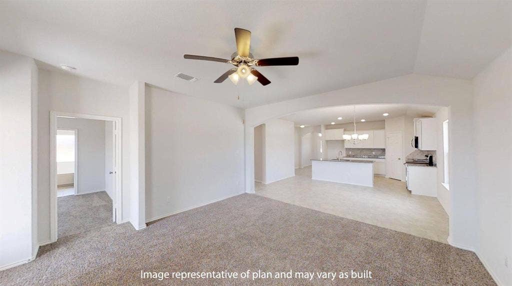 Spacious living area featuring neutral carpeting and a ceiling fan with light fixture