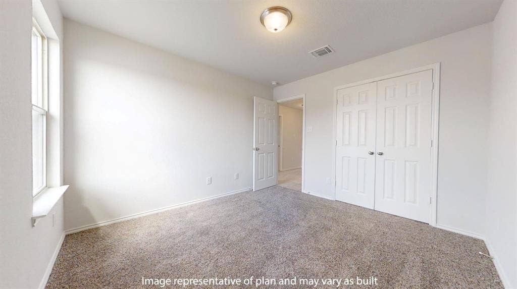 Carpeted room featuring a double-pane window, flush mount ceiling light fixture, white interior walls, and a bi-fold closet with panel doors