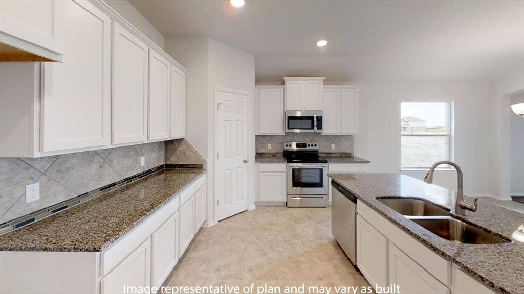 Kitchen featuring white cabinetry, granite countertops, stainless steel appliances, a tile backsplash, and a central island with a double basin sink