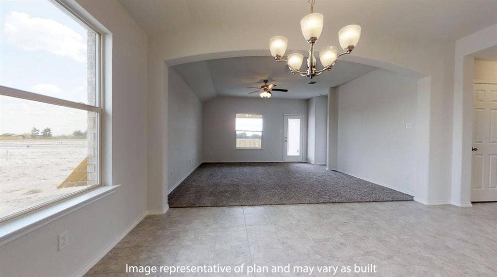 Expansive room featuring tile flooring, a contemporary chandelier, and an arched doorway opening to a carpeted area with a ceiling fan