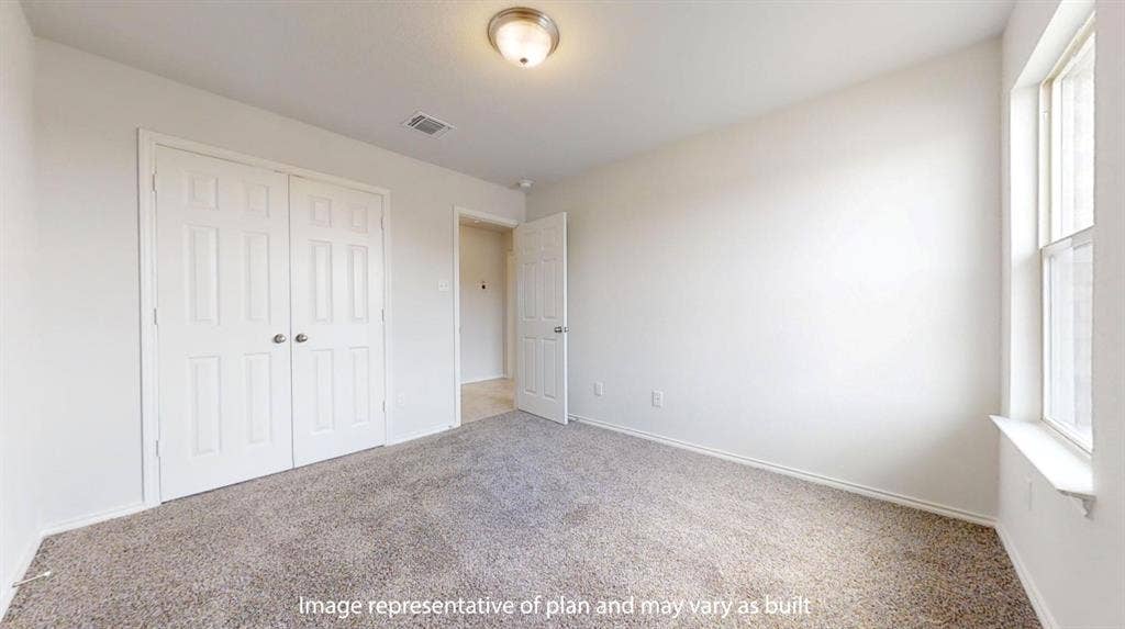 Carpeted room featuring a double-door closet, a single window, and a flush mount ceiling light