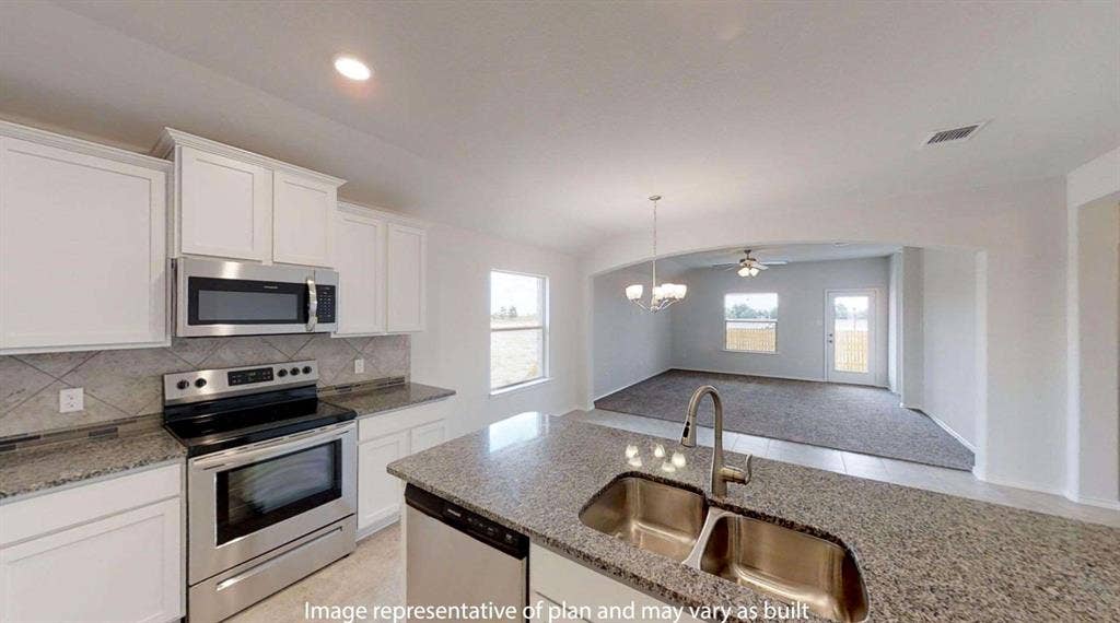 Kitchen featuring granite countertops, stainless steel appliances, a double basin sink with a high-arc faucet, white cabinetry, and a tile backsplash