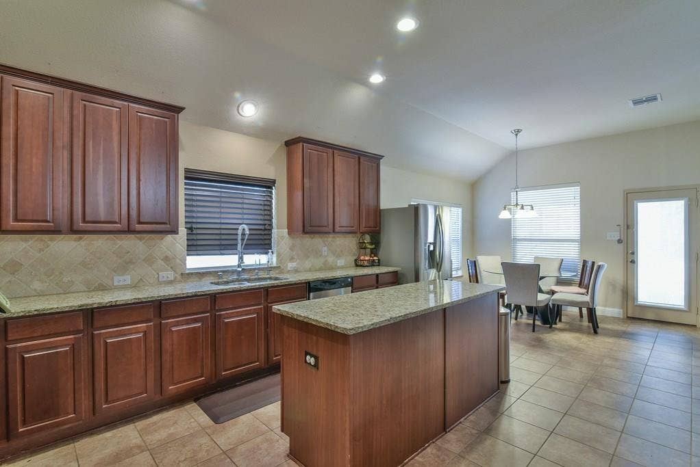 2705 Fox Creek Trail, Arlington, TX 76017 Kitchen featuring dark wood cabinetry, granite countertops, and a neutral tile backsplash