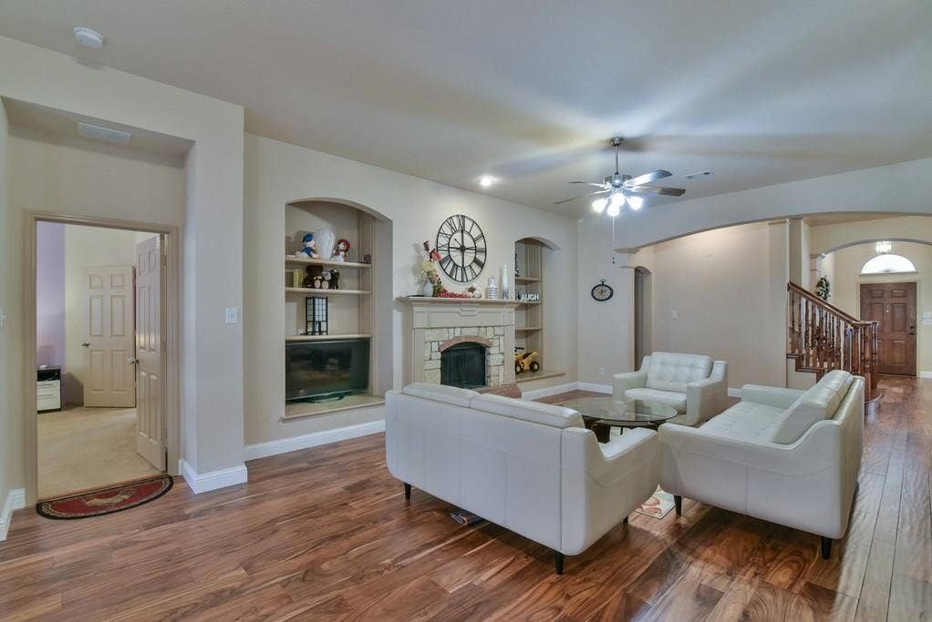 2705 Fox Creek Trail, Arlington, TX 76017 Spacious living area featuring wood-finish flooring, a stone fireplace, and built-in shelving