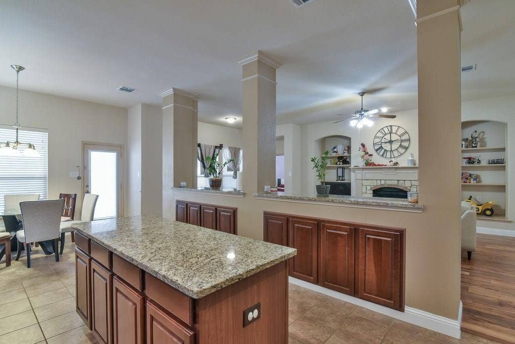 2705 Fox Creek Trail, Arlington, TX 76017 Kitchen island with granite countertop and rich wood-finish cabinetry