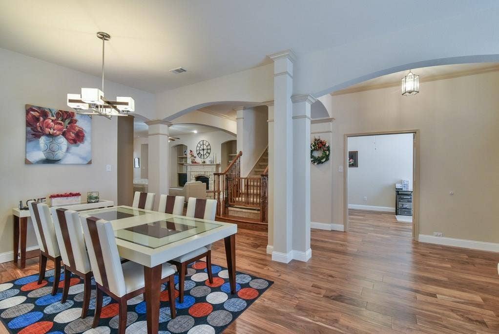 2705 Fox Creek Trail, Arlington, TX 76017 Dining area with wood-finish flooring, featuring a contemporary chandelier and arched doorways